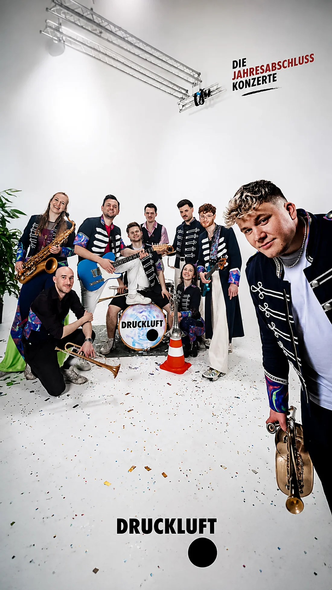 Die Band Druckluft in Uniformjacken mit Bläsern und Konfetti in einem weißen Studio